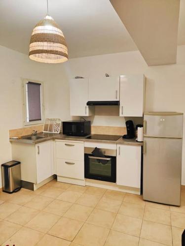 a kitchen with white cabinets and a refrigerator at Appartement des Carmes in Nîmes