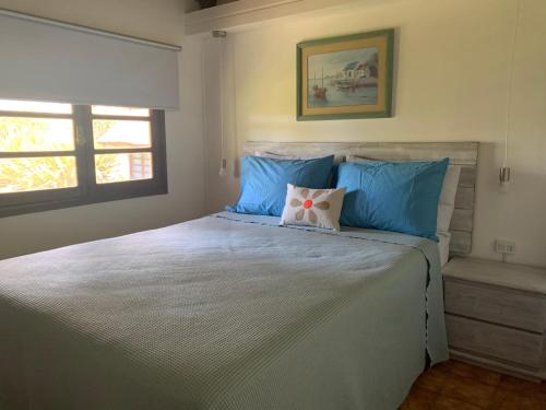 ein Schlafzimmer mit einem großen Bett mit blauen Kissen in der Unterkunft CASA MARÍTIMA EN PORTEZUELO, MALDONADO, URUGUAY in Punta del Este