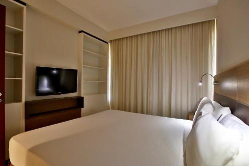 a hotel room with a bed and a television at Quality Hotel & Suítes São Salvador in Salvador