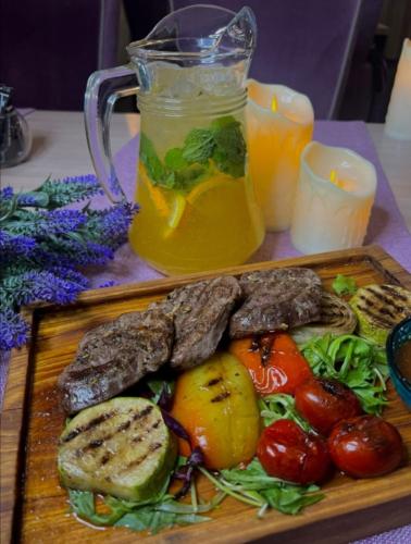 a plate of food with meat and vegetables and a drink at East Palace Hotel in Almaty