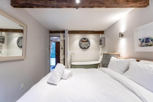 a bedroom with a large white bed and a bathroom at Otters Abode in Blockley