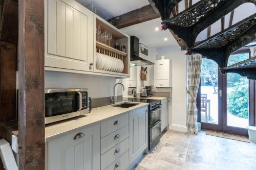 a kitchen with white cabinets and a microwave at Otters Abode in Blockley