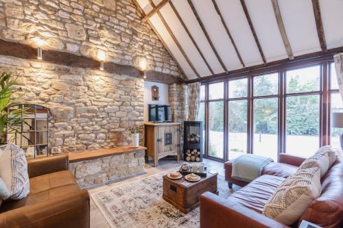a living room with couches and a stone wall at Otters Abode in Blockley