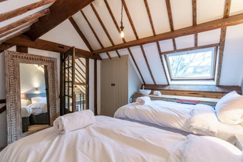 a bedroom with two beds and a mirror at Otters Abode in Blockley