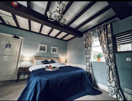 a blue bedroom with a bed and a window at Blenheim House Hotel in Etwall