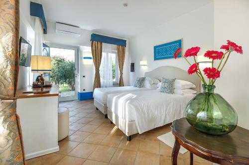 Riva di Palo Resort في لاديسْبولِي: غرفة نوم مع سرير و مزهرية من الزهور على طاولة