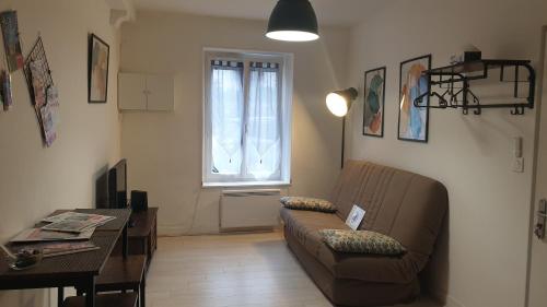 a living room with a couch and a table and a window at Studio meublé et équipé in Ingré
