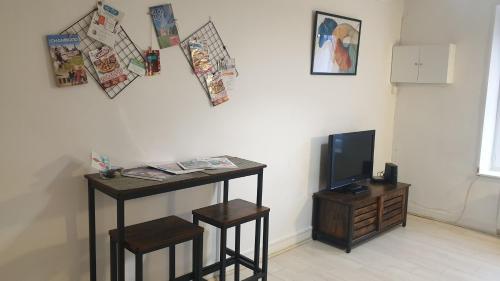 a room with a desk and a tv and a table and stool at Studio meublé et équipé in Ingré
