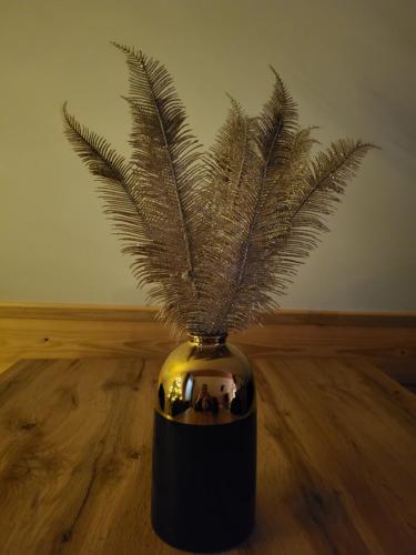 a black and gold vase with a plant in it at Apartament Nad Zaporą in Szlembark