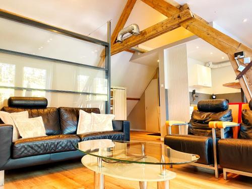 a living room with leather furniture and a glass table at B&B de Muldermolen in Schinnen