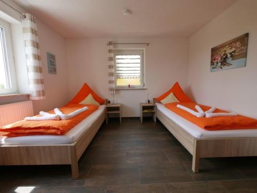 Duas camas num quarto com almofadas laranja em Ferienwohnung 10 em Ochsenhausen