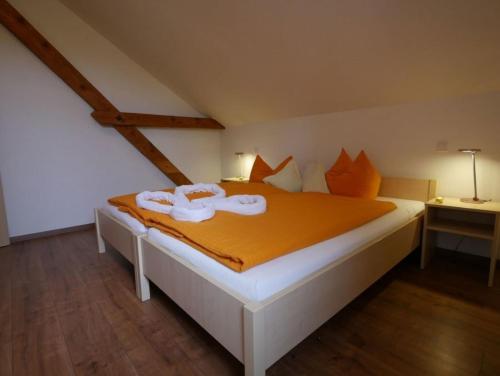 um quarto com uma cama grande com lençóis laranja em Ferienwohnung 7 em Ochsenhausen