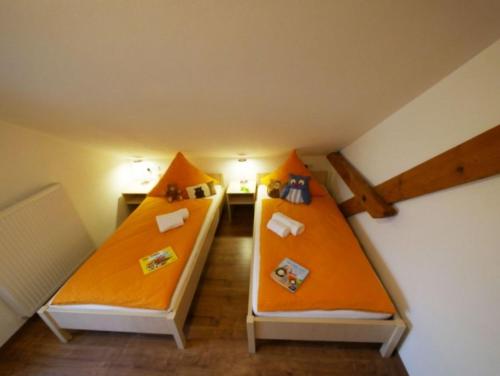 2 camas en una habitación con paredes de color naranja en Ferienwohnung 5 en Ochsenhausen