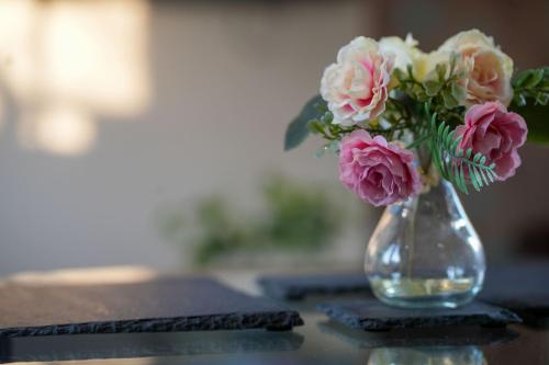 a glass vase with pink and white flowers on a table at The Old Dairy in Boston
