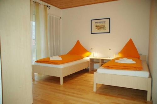 twee bedden in een kamer met oranje lakens bij Ferienwohnung 8 in Ochsenhausen