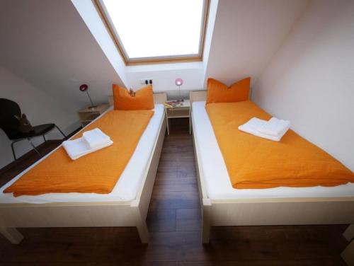 2 letti in una piccola camera con lenzuola arancioni di Ferienwohnung 3 a Ochsenhausen