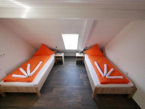 2 camas en un ático con almohadas de color naranja y blanco en Ferienwohnung 11 en Ochsenhausen