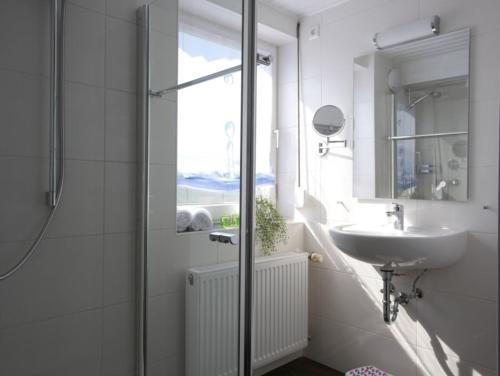 a white bathroom with a sink and a shower at Ferienwohnung 11 in Ochsenhausen