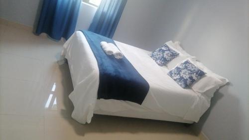 a small bed in a room with blue curtains at Goshen Place in East London