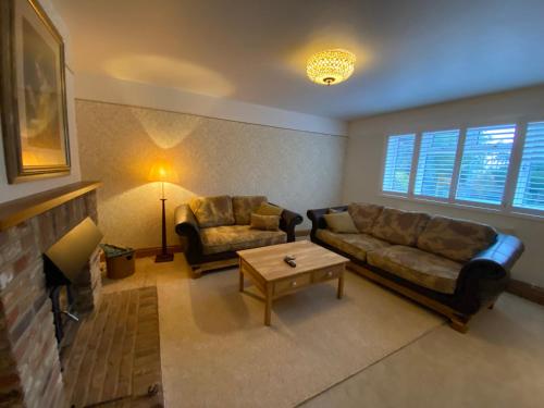 a living room with two couches and a fireplace at Mulberry Cottage near Goodwood in Chichester