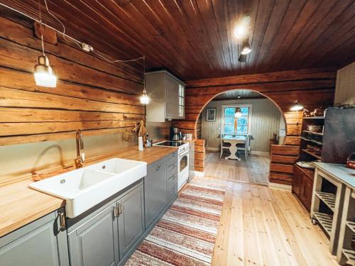 a kitchen with wooden walls and a white sink at Taiga Forest Lodge in Gällivare