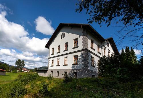 a white house with a black roof on a hill at Apartmány U Aloise in Dolní Morava