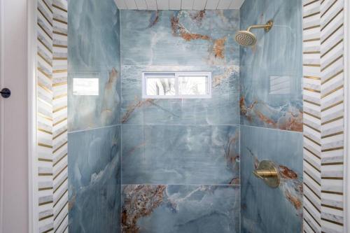 a bathroom with a blue tiled shower with a window at Newly Renovated House-10 Minutes From Downtown in Cincinnati