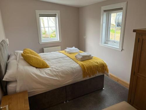 ein Schlafzimmer mit einem Bett mit gelben Decken und zwei Fenstern in der Unterkunft Bixter House - a spacious self-catering property 