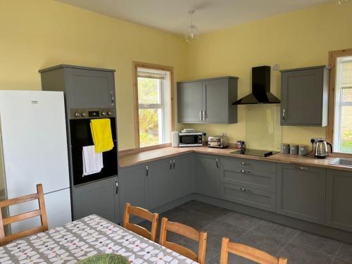 a kitchen with gray cabinets and a table and a refrigerator at Bixter House - a spacious self-catering property 