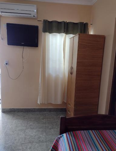1 dormitorio con TV en la pared y vestidor en Habitaciones Gabriel en Termas de Río Hondo
