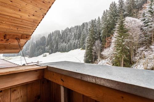 a balcony with a view of a snow covered forest at Schwüwong - Apartment 04 in Kelchsau