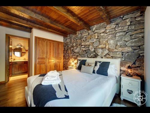 1 dormitorio con 1 cama grande y pared de piedra en CERVI de Alma de Nieve, en Bagergue