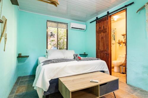 a blue bedroom with a bed and a table at Boutique Rooms at La Junta in Dominical