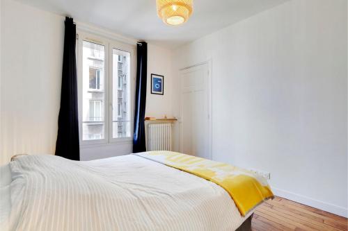 a bedroom with a bed with a yellow blanket on it at Agréable 2 pièces très bien situé in Boulogne-Billancourt