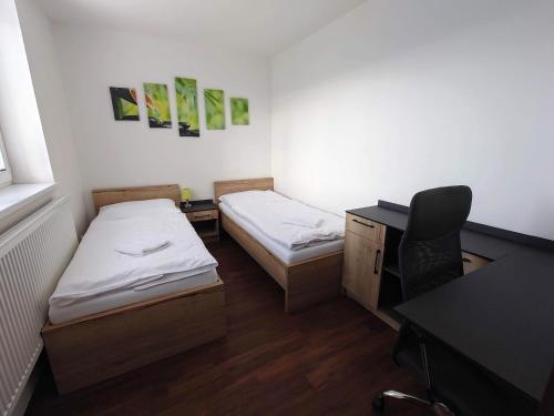 a small room with two beds and a desk and a desk at Penzion Barborka in Olomouc