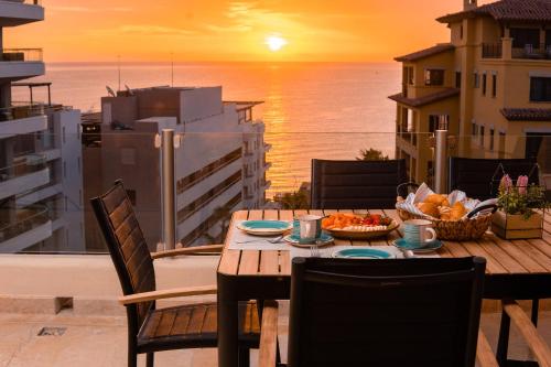 a table and chairs on a balcony with the sunset at Ocean view 4 min walk to Medano Beach in Cabo San Lucas