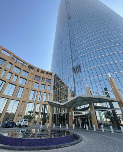 een groot glazen gebouw met een fontein ervoor bij Raffal Tower Apartment in Riyad
