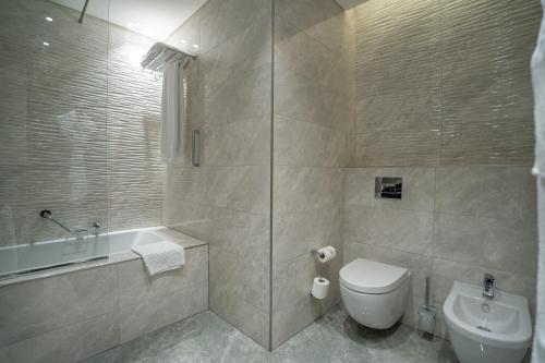 a bathroom with a shower and a toilet and a sink at Grand Millennium Al Seef Basra in Al Başrah