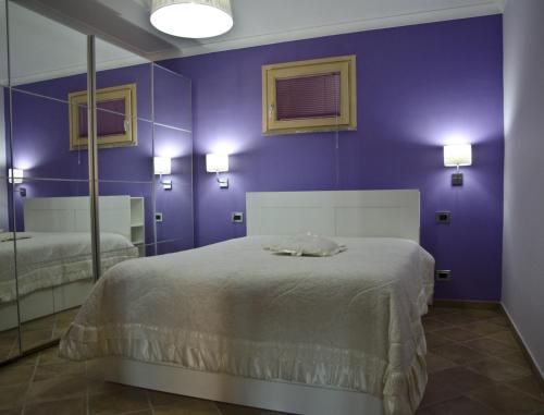 Dormitorio púrpura con cama y espejo en Casa Vacanza Cicirello, en Giardini Naxos
