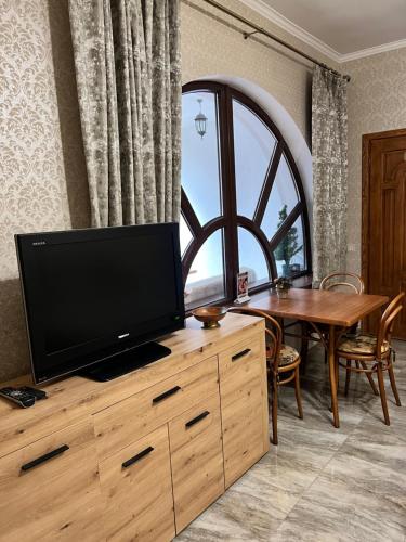 a living room with a flat screen tv on a wooden dresser with a table at Вілла Лісова комфорт in Skhidnitsa
