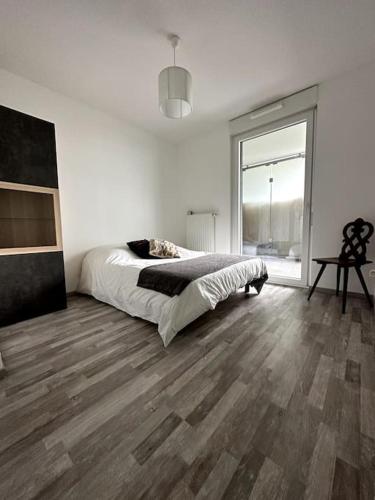 une chambre blanche avec un lit et un parquet dans l'établissement Superbe appartement proche de Strasbourg, à Bischheim