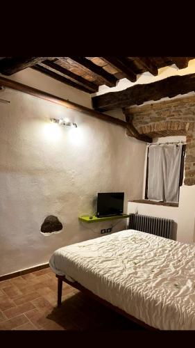 um quarto com uma cama e uma televisão na parede em La mia casa nel Borgo em Scarlino