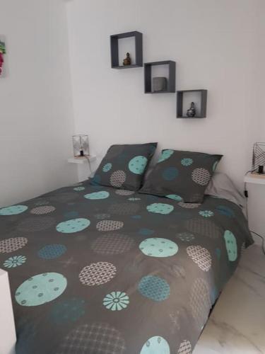 - une chambre dotée d'un lit avec un couvre-lit vert et bleu dans l'établissement logement indépendant avec terrasse 