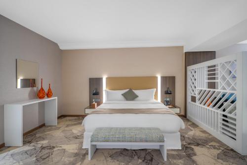a bedroom with a large bed and a staircase at Grand Millennium Al Seef Basra in Al Başrah