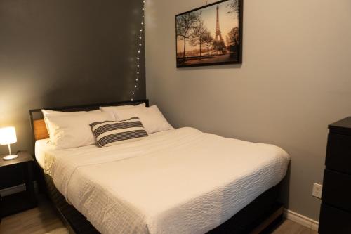 um quarto com uma cama branca e uma fotografia na parede em Cozy Home in Downtown Winnipeg em Winnipeg