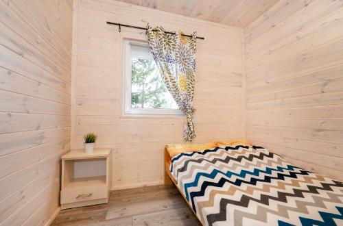 een kleine kamer met een bed en een raam bij Domki Przyjazna Osada in Darłowo