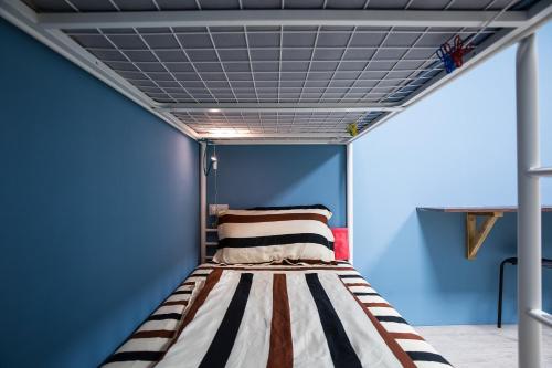 魚池鄉的住宿－日月彩舟 日月潭背包客旅店 Sun Moon Lake Rainbow SUP Hostel，蓝色客房的一张床位,天花板