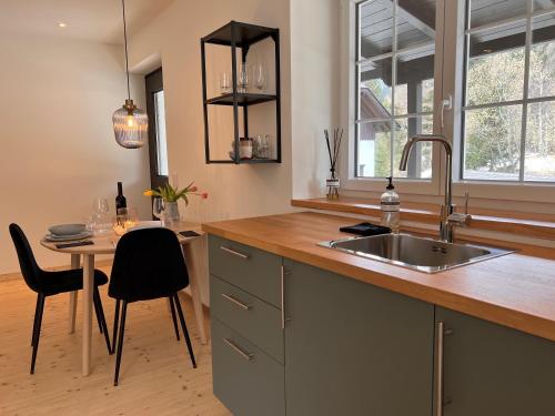 a kitchen with a sink and a table with chairs at Ankogel Lofts Mallnitz in Mallnitz