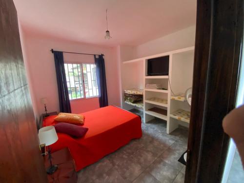 1 dormitorio con cama roja y ventana en Apartamento Los Gladiolos en Salta
