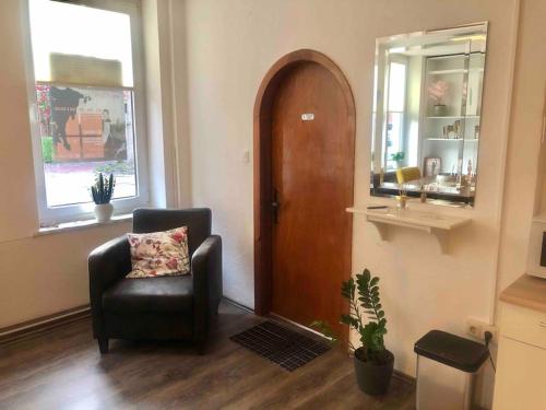 a living room with a chair and a wooden door at Studio Emdecker am Delft in Emden